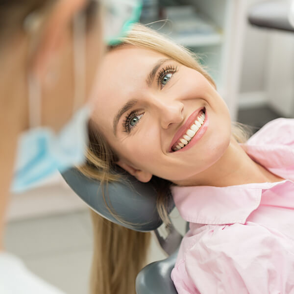  A smiling lady is lying on a dental chair and looks on to her dentist