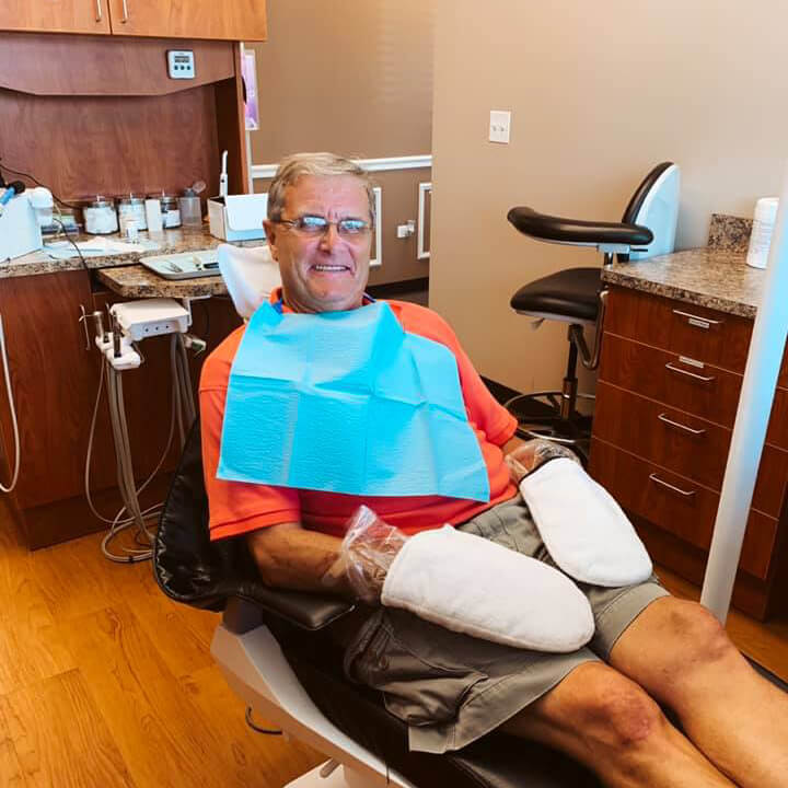 A smiling elderly man in a dentist chair.